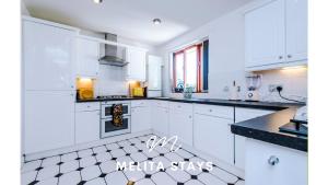 a white kitchen with white cabinets and black counter tops at Spacious and stylish 2 bedroom apartment in Birmingham