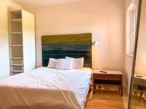 a bedroom with a white bed with a painting on the wall at White shell vilamoura in Maritenda