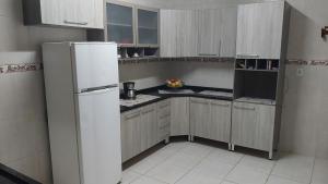 a small kitchen with a white refrigerator and cabinets at Casa Sol & Mar in Itanhaém