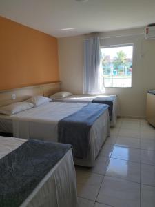 a hotel room with three beds and a window at Porto Carleto Temporadas - Quarto no Portobello Park Hotel in Porto Seguro