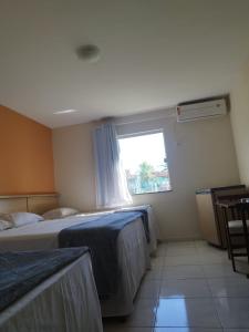 a hotel room with two beds and a window at Porto Carleto Temporadas - Quarto no Portobello Park Hotel in Porto Seguro