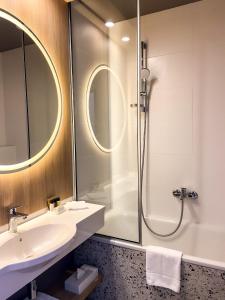 a bathroom with a sink and a shower at CONTI HOTEL VILNIUS, Conference Centre, Restaurant & Bar in Vilnius