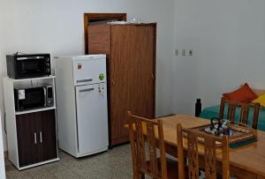a kitchen with a table and a white refrigerator at El Roble in Bahía Blanca +9 photos