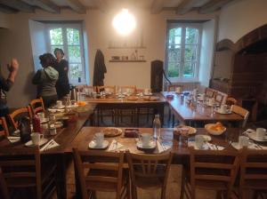 a group of people standing around a dining room table at Chambres d'hôtes l'arche d'Yvann in Campuac