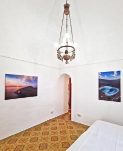 um quarto com paredes brancas e um lustre em La Casa del Sole em Pantelleria