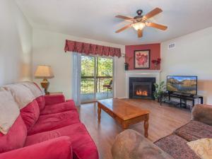 een woonkamer met een rode bank en een open haard bij Riverside Dream Cedar Lodge 103 in Pigeon Forge