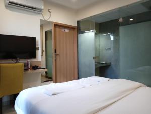 a bedroom with a white bed and a television at Hotel New Centro in Gulbarga