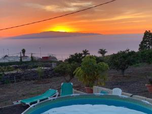 a sunset over the ocean with a pool and chairs at CASA familiar en un entorno natural en Tenerife Sur in Adeje