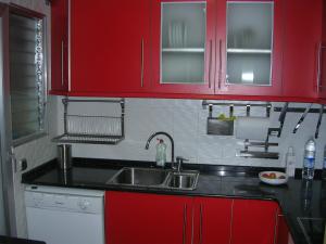 eine Küche mit roten Schränken und einem Waschbecken in der Unterkunft Apartament amb jardí privat i piscina in Salou