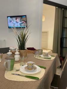un tavolo con piatti e tazze e una TV in camera di Maioliche Apartments a Margherita di Savoia