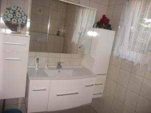 a white bathroom with a sink and a mirror at Haus Idylle Weindorf Duchroth - Helle Souterrain Ferienwohnung in Duchroth