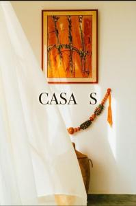 a white curtain hanging on a wall with a painting at Guest House Casa S in Ngaparou