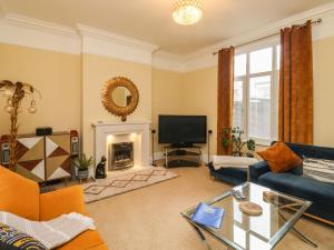a living room with a blue couch and a tv at Russell House in Paignton