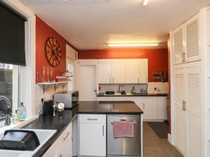 a kitchen with white cabinets and an orange wall at Russell House in Paignton