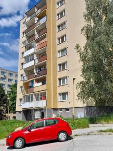 ein rotes Auto, das vor einem Gebäude parkt in der Unterkunft Apartman na kopci in Košice