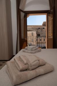 três toalhas sentadas em cima de uma cama com uma janela em Giulietta Normanna em Sciacca