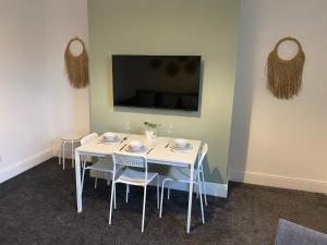 einen weißen Tisch mit Stühlen und einen TV an der Wand in der Unterkunft Overhill 3 bedroom flat 5 beds, free parking, ideal for Contractors in Gateshead