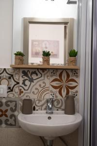 uma casa de banho com lavatório, espelho e plantas em Giulietta Normanna em Sciacca