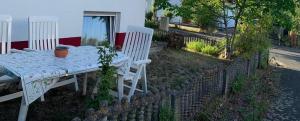Biały stół i krzesła siedzące na boku domu w obiekcie Haus Idylle Weindorf Duchroth - Helle Souterrain Ferienwohnung w mieście Duchroth
