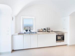 a white kitchen with a sink and a window at Trulleria Alchimia in Selva di Fasano