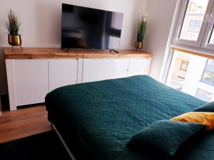 a bedroom with a bed and a flat screen tv at Fachpol Apartments Sienkiewicza 22D in Zamość