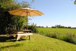 un tavolo da picnic con un ombrellone accanto a un campo di Vakantie Appartement Klavertje 4 in Laren Gld a Laren