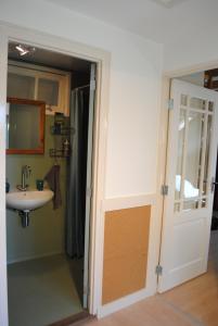 baño con lavabo, espejo y puerta en Vakantie Appartement Klavertje 4 in Laren Gld, en Laren