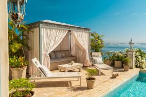 eine Terrasse mit einem Bett und Stühlen neben einem Pool in der Unterkunft Villa Caprichosa in Taboga