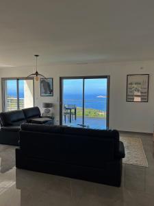 a living room with a black couch and a view of the ocean at Appartement 140M2 villa cargèse in Cargèse