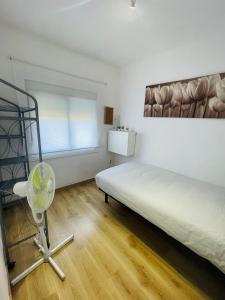a white room with a bed and a fan at Beach Apartment Barca 6 in Barcelona