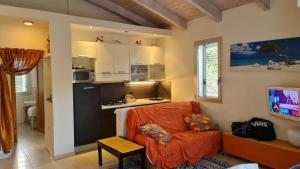 ein Wohnzimmer mit einem orangenen Stuhl und eine Küche in der Unterkunft Residence La Settima in Milano Marittima