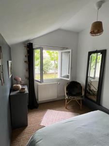 a bedroom with a bed and a chair and a window at La maison du Mauret in Andernos-les-Bains