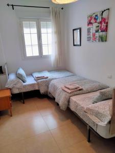 een kamer met 3 bedden en een raam bij Apartamento grande centrico in Antequera