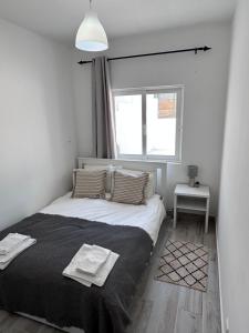 1 dormitorio con 1 cama con manta negra y ventana en Casa Maria João, en Lagos