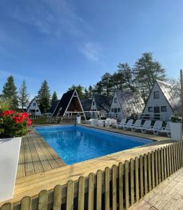 a swimming pool with chairs and a fence at Soul Camp Nowęcin in Łeba