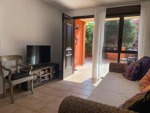 ein Wohnzimmer mit einem Flachbild-TV und einem Sofa in der Unterkunft Cozy apartment with large terrace next to the pool in La Tejita