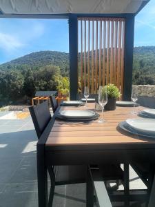 a wooden table with plates and wine glasses on a balcony at Golden residence with heated pool in Vinišće