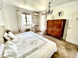 1 dormitorio con 1 cama blanca grande con lámpara de araña en viilla D Aurus, en Vallauris