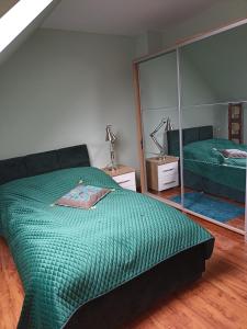 - une chambre avec un lit vert et un miroir dans l'établissement ELEKTRA, à Stare Bielice