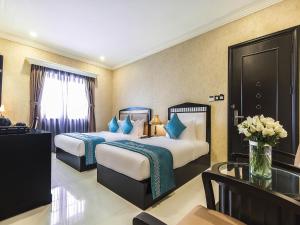 ダナンにあるIBIZA Danang Riverfront Hotelのベッド2台とテーブルが備わるホテルルームです。