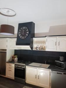 - une cuisine avec une horloge au-dessus d'une cuisinière dans l'établissement Gîte Stevalou, à Labarthe-Rivière