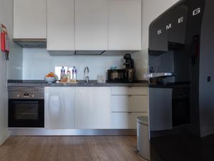 een keuken met witte kasten en zwarte apparaten bij Apartamento Deluxe AM in Quarteira