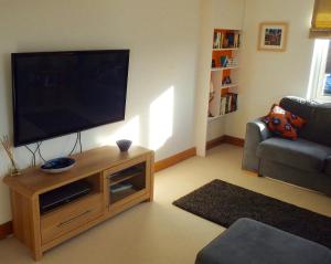 a living room with a flat screen tv on a wooden stand at The Laurels in Westwood