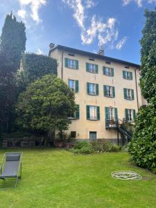 un grand bâtiment avec une pelouse devant lui dans l'établissement Casa Vittoria, à Tremezzo