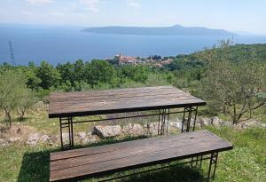 eine Holzbank auf einem Hügel mit Blick auf das Wasser in der Unterkunft Casa Delle Olive in Mošćenička Draga
