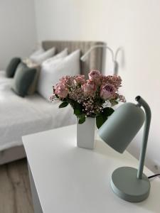 einen weißen Tisch mit einer Vase rosa Blumen drauf in der Unterkunft Wanderlust Petrisberg - Studio 54 in Trier