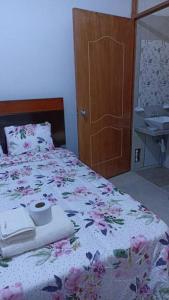 - une chambre avec un lit, une couette en fleurs et un lavabo dans l'établissement CASA TALLÁN 2 habitaciones wifi Cocina baño privado Jr Junin 263 barrio norte Piura, à Piura