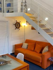 - un canapé orange dans un salon avec un escalier dans l'établissement Casa Nadip, à Ustica