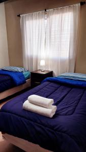 1 dormitorio con 2 toallas en una cama azul en Departamento en zona Alto Maipú en Maipú