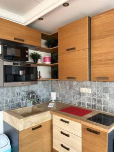 una cocina con armarios de madera y fregadero en Sunny/stylish rooftop home/private balcony shared jacuzzi en Budapest